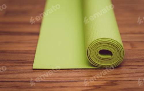Preview: Exercise and workout, green rolled up yoga mat on hardwood floor
