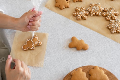Preview: Women's hands decorate sugar icing homemade traditional New Year's cookies snowflake gingerbread man
