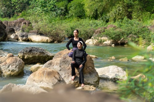 Preview: Asian Indonesian Women Relaxing and Meditating on River Rocks in Natural Setting