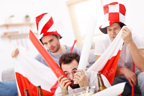Preview: Happy male friends cheering and watching sports on tv