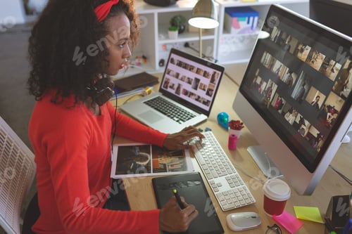 Preview: Young female graphic designer using graphic tablet at desk in a modern office