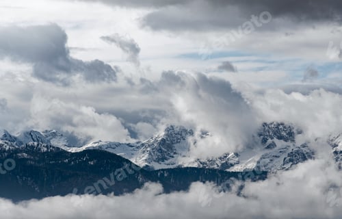 Preview: Epic landscape view of snow capped mountain peak in clouds.