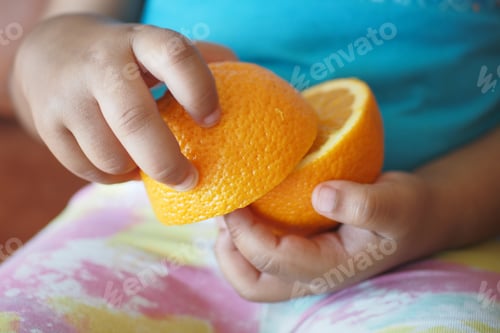 Preview: A Child is Happily Holding a Bright Orange Half in Soft, Warm Natural Light, Exhibiting Joy