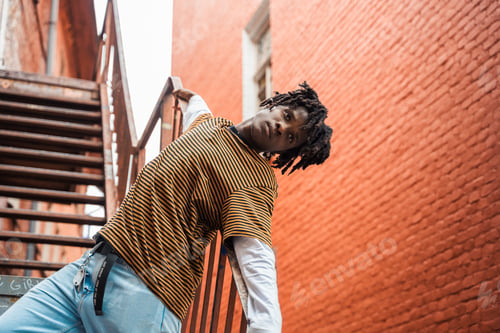 Preview: Portrait of young handsome stylish black man with natural hair dreadlocks. Afroamerican guy. Stairs,