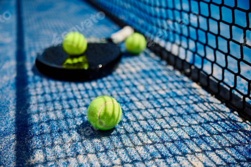 Preview: Yellow balls and a racket on paddle tennis court.