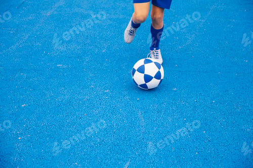 Preview: Little unrecognizable boy playing soccer of blue background