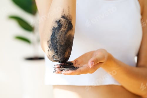 Preview: Woman cleans skin of the body with coffee scrub in bathroom.
