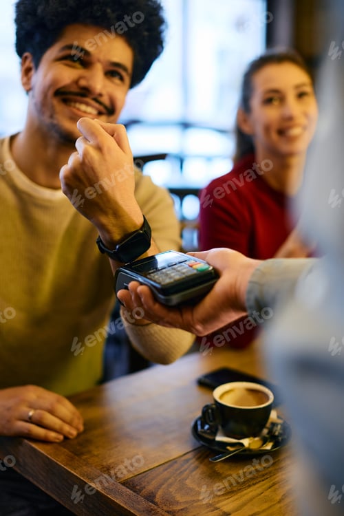 Preview: Close-up of contactless payment with smart watch in a pub.