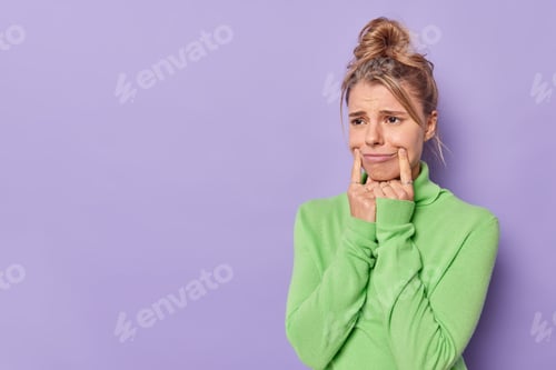 Preview: Photo of upset young European woman stretches mouth in forced smile has sad expression wears casual