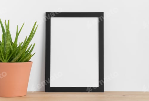 Preview: Black frame mockup with a aloe vera in a ceramic pot on a wooden table. Portrait orientation.