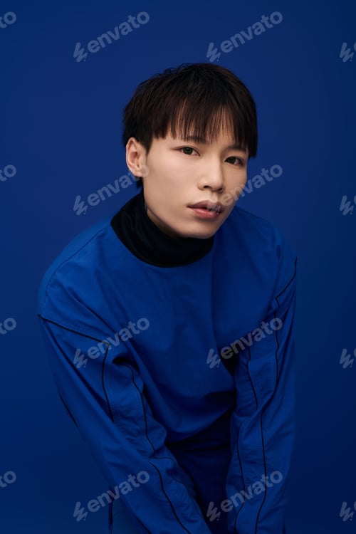 Preview: Young handsome asian man in stylish blue attire poses against a vibrant blue background