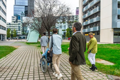 Preview: Diverse business people walking city street with wheelchair user
