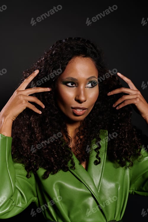 Preview: Striking beauty with curly hair poses confidently in vibrant green outfit against dark backdrop