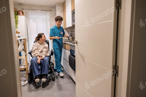 Preview: Caregiver cooking for woman with disability in kitchen