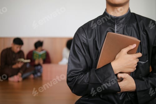 Preview: Close-up Of Unrecognized Muslim Man Holding Holy Qur'an Against Muslim Prayer Background