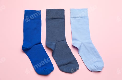 Preview: Different blue socks on light pink background, flat lay
