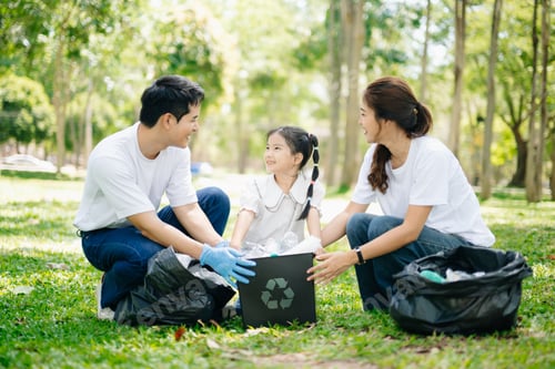 Preview: Asian parents and child collect trash in the forest, promoting recycling, unity, and ecology.