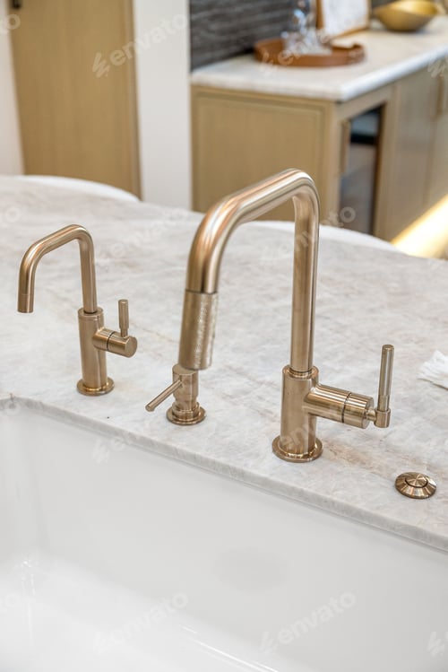 Preview: Modern gold kitchen faucet on marble countertop.