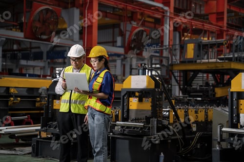 Preview: Two workers in a factory looking at a laptop