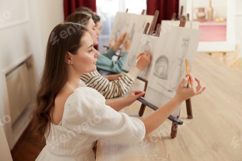Preview: Group of women with easels learning to draw at wooden table in class