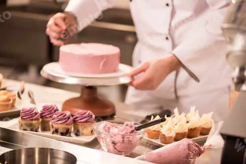 Preview: cropped shot of confectioner making cake in restaurant kitchen