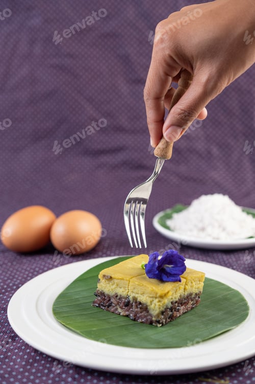 Preview: The handle that is about to insert the black sticky rice dessert with custard on the banana leaf.