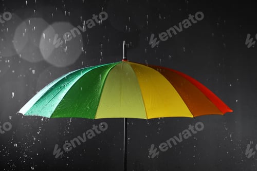 Preview: Bright umbrella under rain on dark background