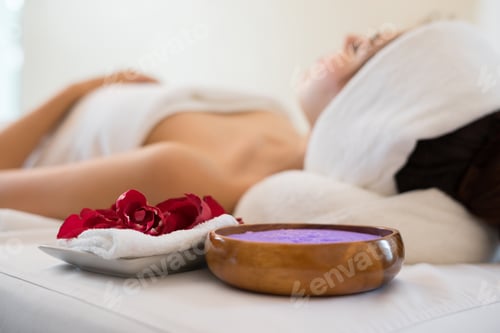Vista previa: Beautiful smiling woman with flowers resting in the spa before massage.