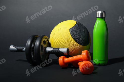 Preview: Medicine ball, dumbbells, ab wheel and water bottle on black background