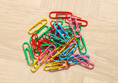 Preview: Many colorful paper clips on wooden table, top view