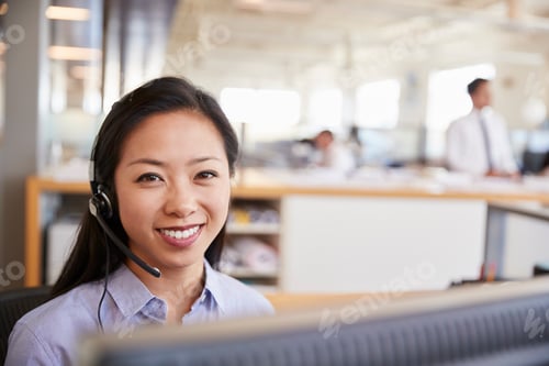 Preview: Young Asian woman working in a call centre smiling to camera