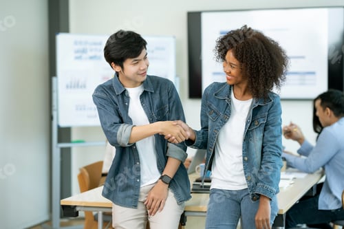 Preview: Two colleagues shaking hands in an office. Corporate environment and teamwork concept