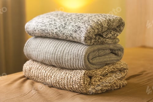 Preview: A pile of knitted winter or autumn sweaters on the wood bed. Warm comfortable clothes.