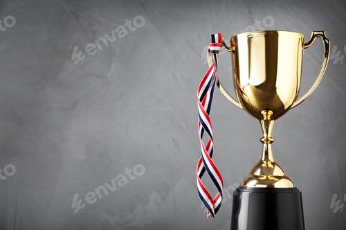Preview: Golden trophy cup with ribbon on grey background. Space for text