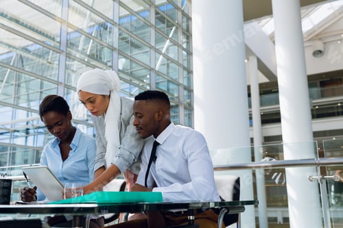 Preview: Male and females executives discussing over digital tablet at desk