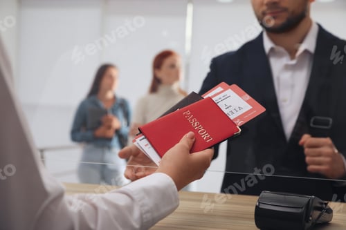 Preview: Agent giving passports with tickets to client at check-in desk in airport, closeup