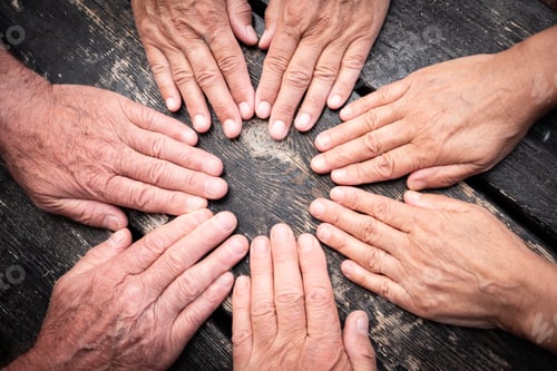 Preview: Caucasian hands touch each other like a seance. Group of people women and men. Dark wooden table