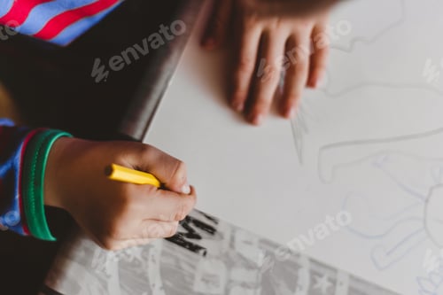 Preview: High angle closeup shot of a little child drawing with a pencil