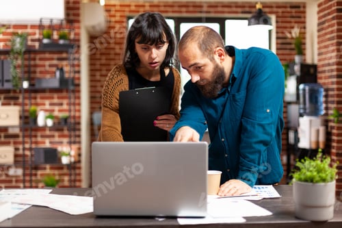 Preview: Communication team looking at management strategy using laptop analyzing business paperwork