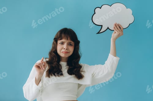 Preview: Confused Woman Holding Blank Speech Bubble Against a Blue Background