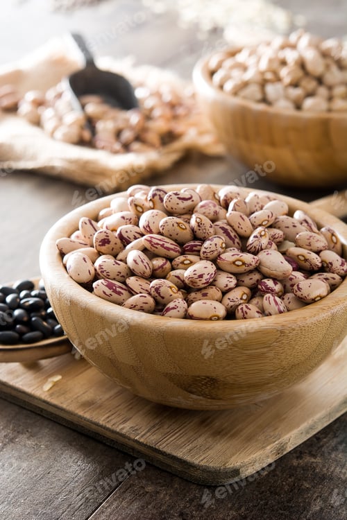 Preview: Borlotti beans filling wooden bowl on rustic kitchen table