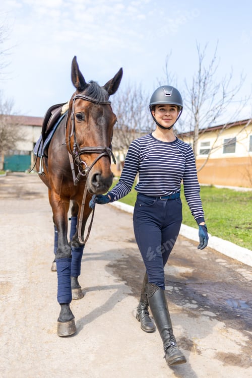 Preview: Young jockey teen girl walking with the horse before training
