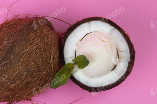 Preview: Vanilla ice cream balls in fresh coconut halves decorated with mint leaves on a pink background
