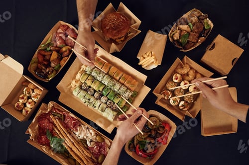 Preview: Top view of table with food on it, hands of the people taking it, eating. Meat, sushi, vegetables