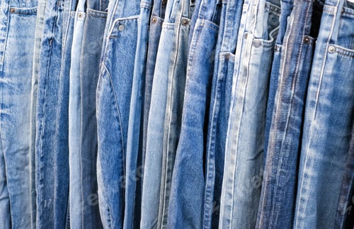 Preview: A lot of jeans hang on a hanger in the store. A row of denim pants on a hanger in the store.