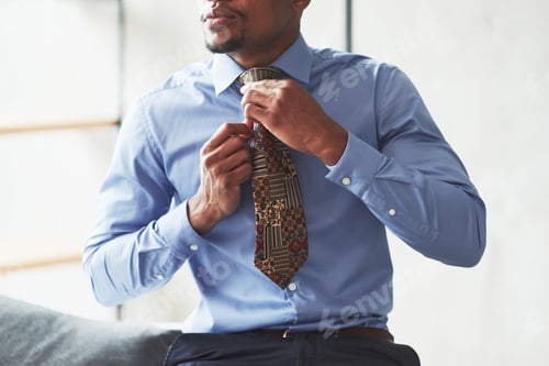 Preview: Man Adjusting his Tie in Preparation for Work