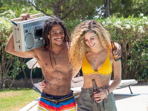 Preview: Interracial couple, black man and Caucasian woman walk with a cassette radio by the pool.