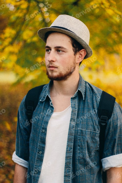 Preview: Vertical selective focus shot of an attractive guy in an autumn park