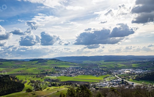 Preview: A town with roads, fields, pastures against the backdrop of silhouettes of hills and a cloudy sky