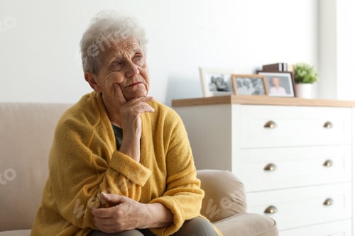 Aperçu: Thoughtful elderly woman on sofa at home